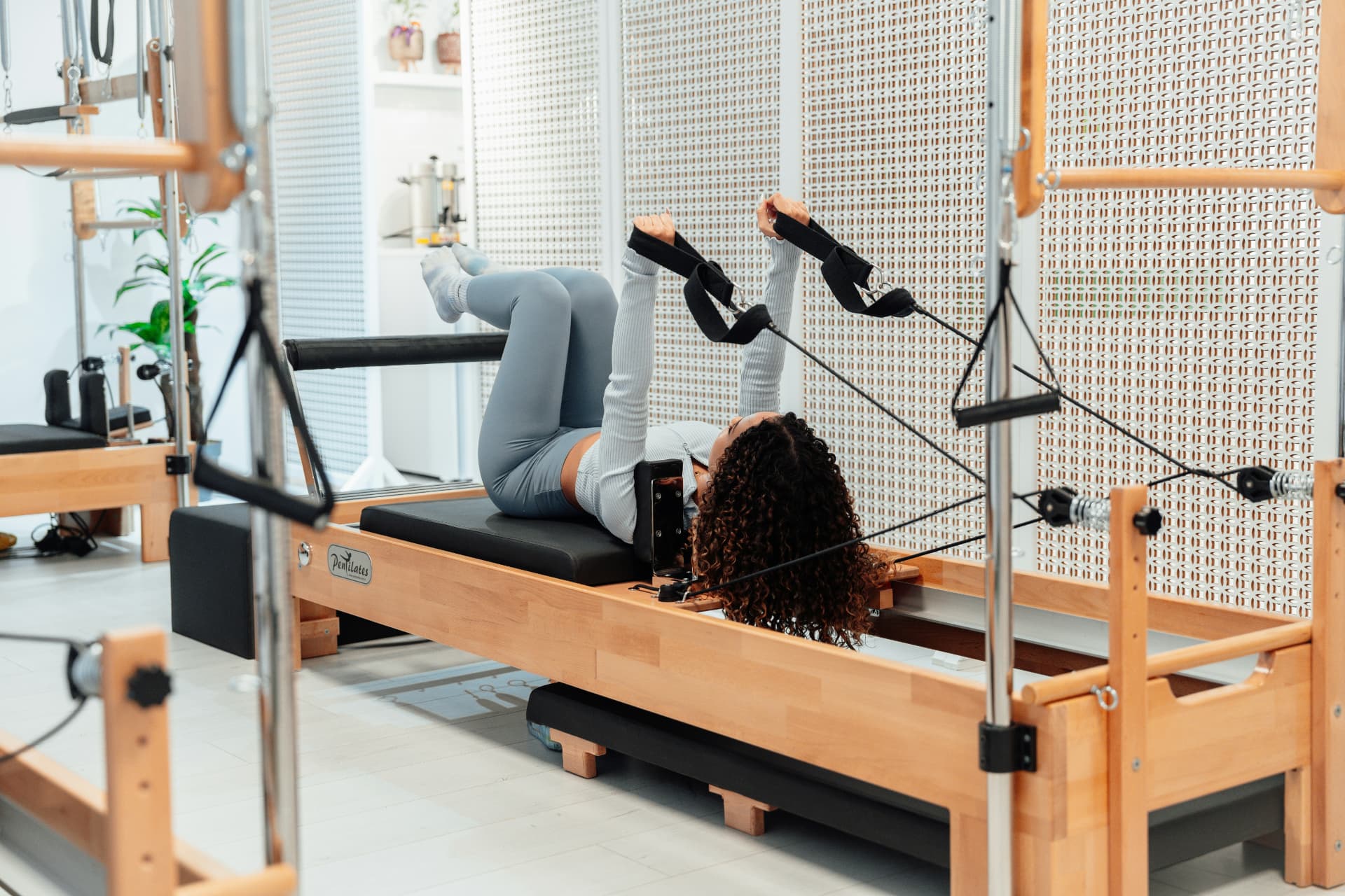 Pratiquante utilisant les sangles d’un Reformer avec Tour en bois