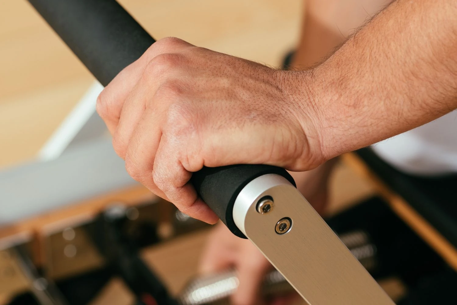 Réglage de la barre de pieds avec les ressorts d’un Reformer en arrière-plan
