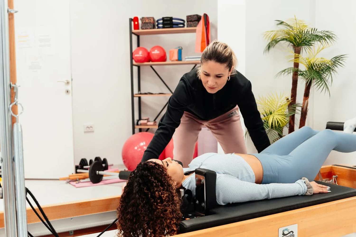 Instructrice accompagnant une pratiquante sur un Reformer Pilates