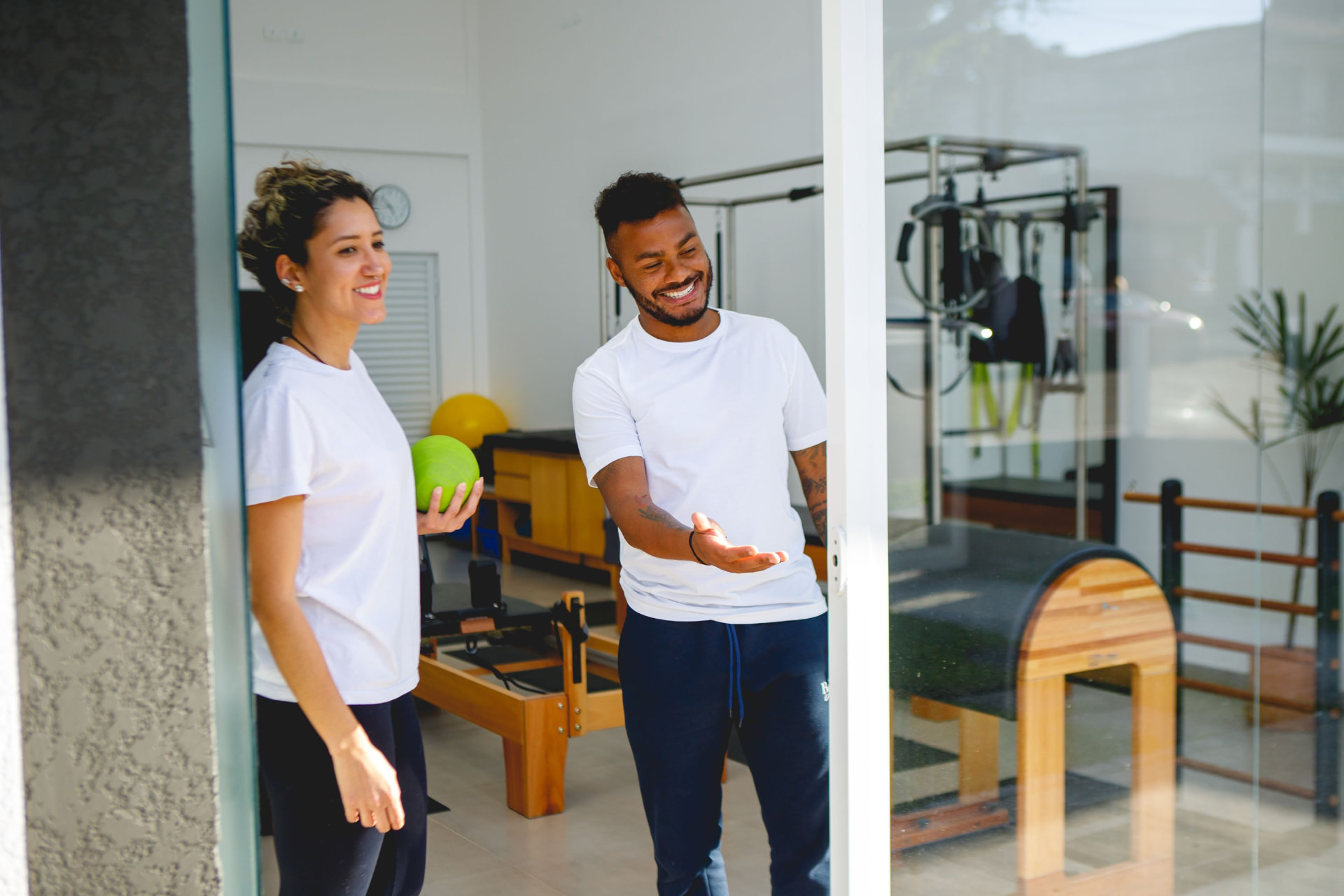 Deux professionnels accueillant dans un studio Pilates équipé de machines en bois